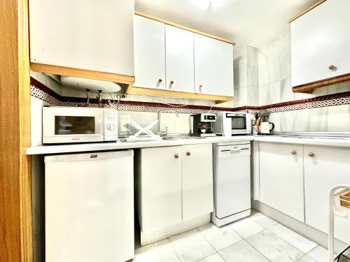 a white kitchen with white cabinets and appliances at Acogedor Apartamento en Sierra Nevada in Sierra Nevada