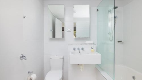 a white bathroom with a toilet and a sink at One Mile Retreat in Anna Bay