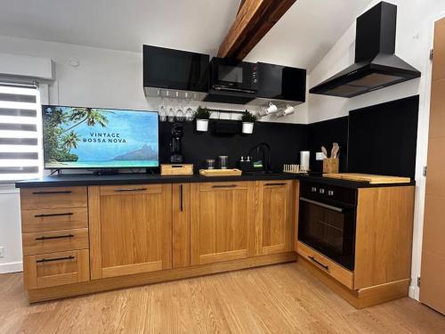 Il comprend une cuisine avec des placards en bois et une télévision murale. dans l'établissement Studio cosy rémois, à Reims