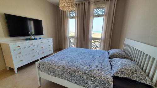 a bedroom with a bed and a dresser with a television at El Gouna Mangroovy Residence Sea View - kitesurfing in Hurghada