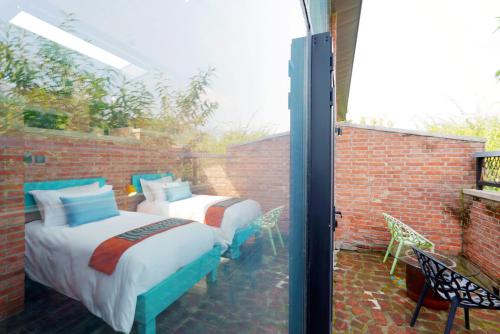 two beds on a patio with a brick wall at Brickyard Retreat at Mutianyu Great Wall Adjoin to Mutianyu Great Wall - Room with the View of Great Wall - Chinese massage experience - Vehicle Shuttle Service - International Catering - SPA& Nail Beauty Facilities in Huairou