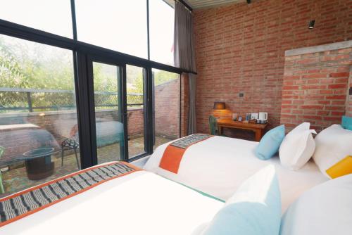 two beds in a room with a large window at Brickyard Retreat at Mutianyu Great Wall Adjoin to Mutianyu Great Wall - Room with the View of Great Wall - Chinese massage experience - Vehicle Shuttle Service - International Catering - SPA& Nail Beauty Facilities in Huairou