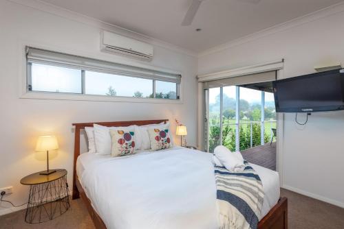 a bedroom with a bed and a large window at Kulang Retreat in charming Broke with Large Swim Spa and games room suits up to 14 guests in Broke