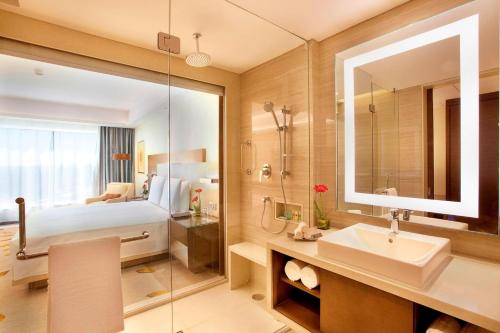 a bathroom with a bed and a sink and a mirror at Courtyard by Marriott Bhopal in Bhopal