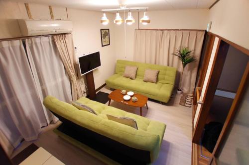 a living room with a green couch and a table at Honmachi House in Tokyo