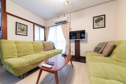 a living room with two green couches and a coffee table at Honmachi House in Tokyo