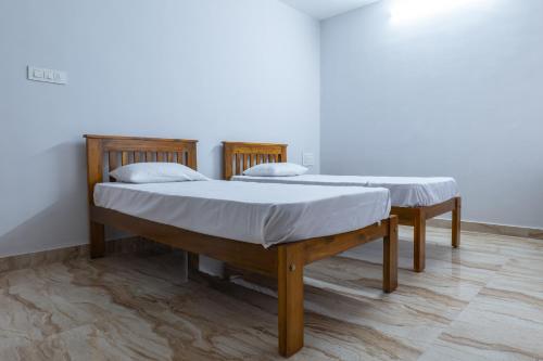 two twin beds in a room with wood floors at Rashra Residency in Manipala