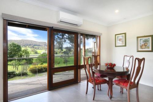 a dining room with a table and a balcony at Belaradah on Stefani Estate Winery in Healesville