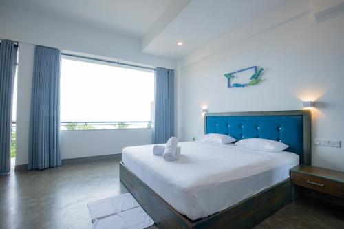 a bedroom with a large bed and a large window at Somerset Mirissa Blue in Mirissa