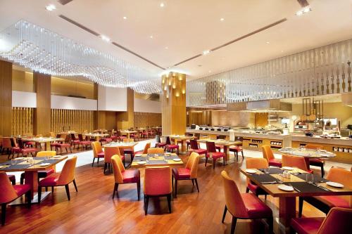 a restaurant with tables and chairs and a kitchen at Courtyard by Marriott Bhopal in Bhopal