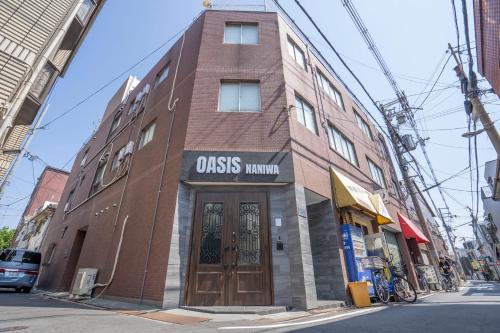 ein braunes Backsteingebäude mit einem Schild auf der Vorderseite in der Unterkunft OASIS NANIWA in Osaka