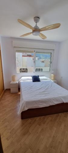 een slaapkamer met een groot bed met een plafondventilator bij MAGNÍFICO ÁTICO EN EL CENTRO DE DENIA in Denia