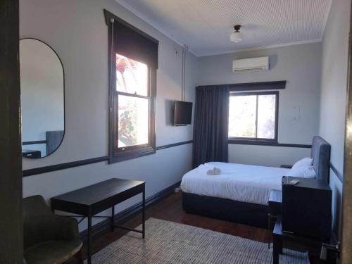 a bedroom with a bed and a desk and a window at The Federal Hotel in Kalgoorlie