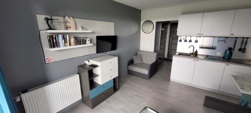 a small kitchen with white cabinets and a television at Sea Power Horyzont Apartament 25 PICCOLO in Jastrzębia Góra