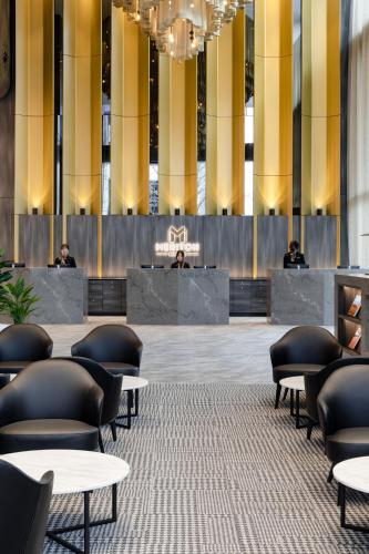 a lobby with tables and chairs in a building at Meriton Suites Canberra in Canberra
