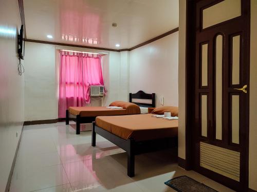 een kamer met 2 bedden en een raam met roze gordijnen bij El Juliana Hotel in Vigan