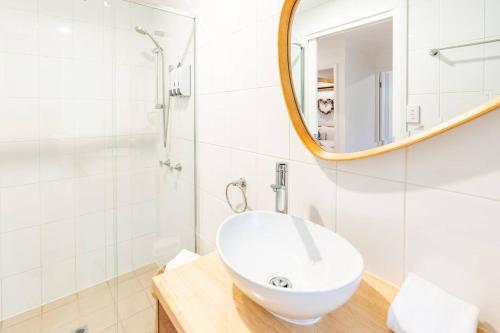 a white bathroom with a sink and a mirror at Woodlands Seaside - Coastal Calm in Avoca Beach in Avoca Beach