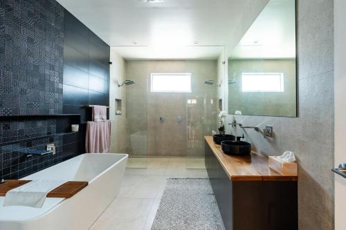 ein großes Bad mit einer Badewanne und einer Dusche in der Unterkunft On The Corso - Sun-soaked Serenity with Lake Access in Gorokan
