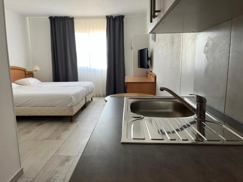 uma casa de banho com um lavatório e um quarto com uma cama em RESID'ARTEL em Fos-sur-Mer