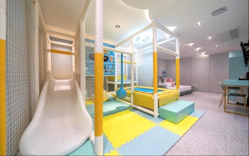 Jangyu Almond Kids Hotel في Gimhae: غرفة لعب للأطفال مع زحليقة فيها