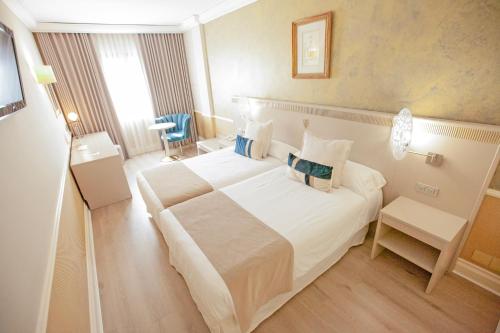 una habitación de hotel con una gran cama blanca y una silla en Hotel Alfonso VIII, en Soria