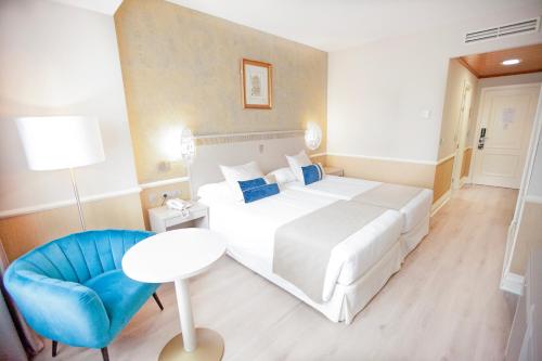 a hotel room with a large bed and a blue chair at Hotel Alfonso VIII in Soria