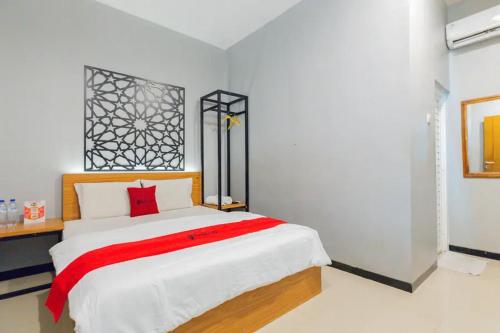 een slaapkamer met een groot bed en een rode deken bij RedDoorz @ Manukan Surabaya in Surabaya