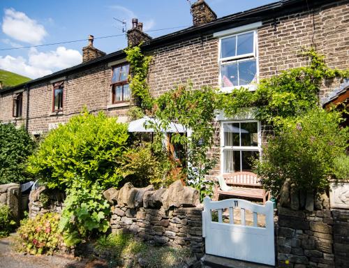 a brick house with a white gate in front of it at Beautiful Country Cottage in Hayfield