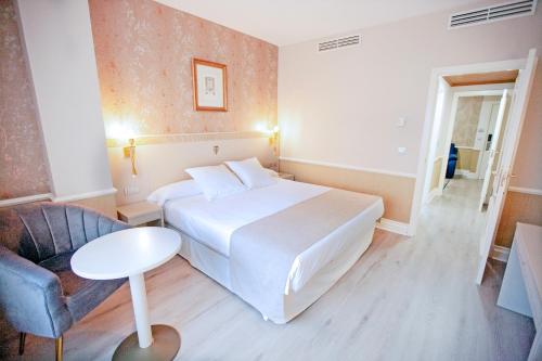 a hotel room with a white bed and a chair at Hotel Alfonso VIII in Soria