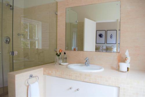 a bathroom with a sink and a shower with a mirror at Le Habitat 6 in Franschhoek