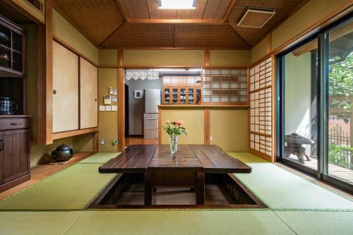 Una habitación con una mesa de madera con flores. en Baikoen en Fukuoka