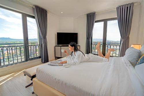 Eine Frau auf einem Bett in einem Hotelzimmer in der Unterkunft Rex Quang Binh Hotel in Dong Hoi