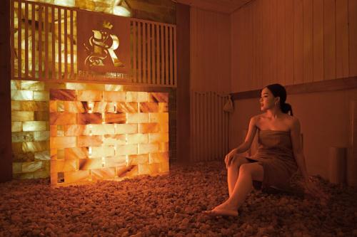 a woman sitting on the floor next to a brick wall at Rex Quang Binh Hotel in Dong Hoi