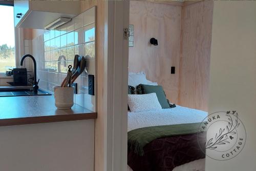 1 dormitorio con cama, ventana y lavamanos en Kanuka Cottage en Whitianga