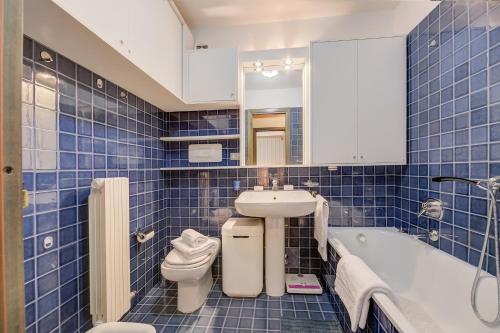 baño de azulejos azules con lavabo y aseo en Appartamento Alpetta 37 Ski In - Ski Out - Happy Rentals, en Sestriere