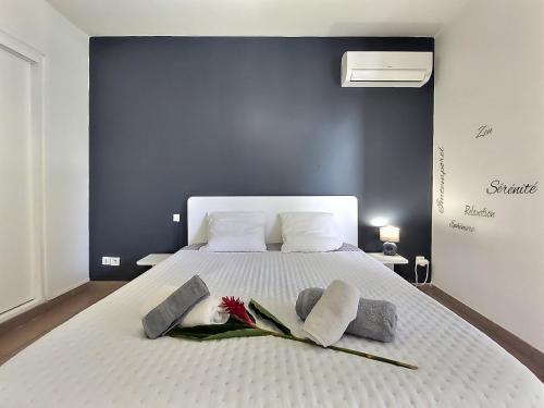 ein weißes Bett mit zwei Handtüchern und Blumen darauf in der Unterkunft Appartement Le Chadec, 1 chambre, piscine dans la résidence, belle plage à 900m in Le Diamant