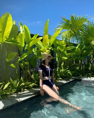 a girl in a hat sitting in the water at Estrella Boutique Hotel in Da Nang