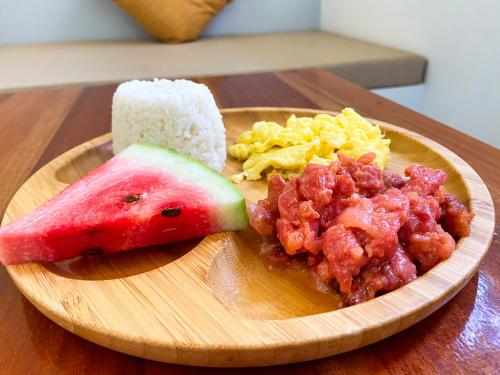 a plate of food with a slice of watermelon and scrambled eggs at Bathala Resort in Panglao