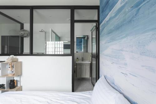 a bedroom with a white bed and a large painting on the wall at Long Stay Here in Tainan