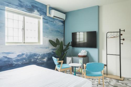 a bedroom with blue walls and a bed and chairs at Long Stay Here in Tainan