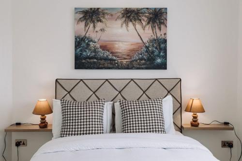 a bedroom with a bed with two lamps and a painting on the wall at Adrich Properties East Legon in East Legon