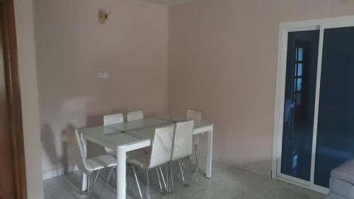 a white dining room table with white chairs and a window at MediSweet Apartments Meublés in Yaoundé