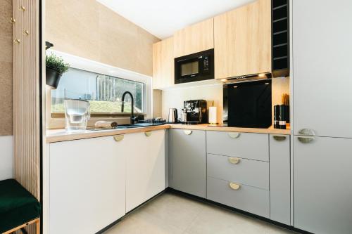 a kitchen with white cabinets and a black microwave at Domki Bliżej Chmur in Duszniki Zdrój