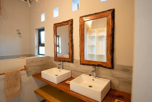 a bathroom with two sinks and two mirrors at Bela Flor Beach Front Apartments in Inhambane