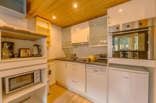 une cuisine avec des armoires blanches et un plafond en bois dans l'établissement Résidence Grand Roc - Campanules 322 - Happy Rentals, à Chamonix-Mont-Blanc