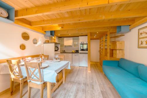 une cuisine et une salle à manger avec une table et un canapé bleu dans l'établissement Résidence Grand Roc - Campanules 322 - Happy Rentals, à Chamonix-Mont-Blanc
