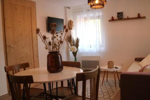 - un salon avec une table et un vase orné de fleurs dans l'établissement Entre vignes et montagnes, à Ayse