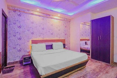 a bedroom with a white bed and a purple wall at Super OYO Hotel Vivaan Residency in Rohtak