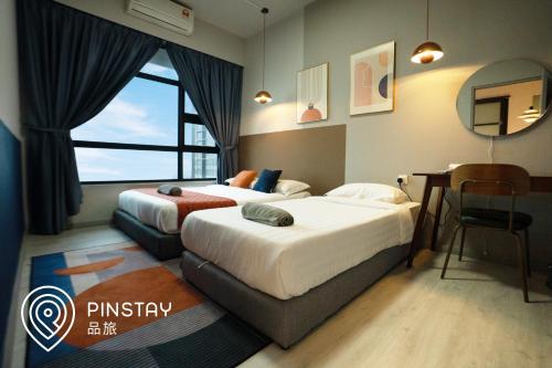 a bedroom with two beds and a desk and a mirror at Jesselton Quay by Pinstay in Kota Kinabalu