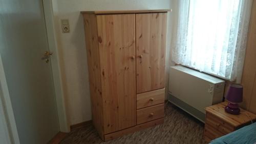 a bedroom with a wooden cabinet next to a window at Haus Katharina in Loissin